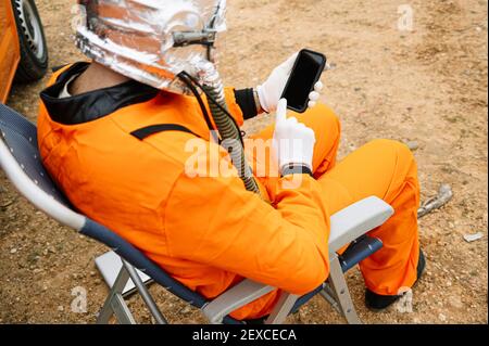 Man dressed as astronaut using smart phone Stock Photo