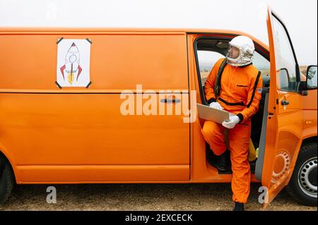 Man dressed as astronaut using laptop Stock Photo