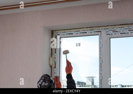 Tiraspol, Moldova - March 2, 2021: Installation of windows. The builder installs a pvc window brand WDS in the apartment of an apartment building. Stock Photo