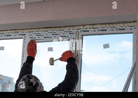 Tiraspol, Moldova - March 2, 2021: Installation of windows. The builder installs a pvc window brand WDS in the apartment of an apartment building. Stock Photo