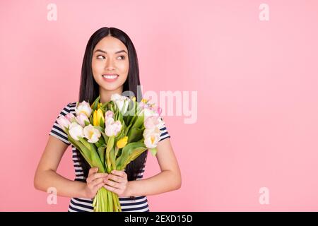 Photo portrait of brunette girl smiling received tulips bunch looking blank space dreamy isolated on pastel pink color background Stock Photo