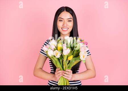 Photo portrait of brunette girl smiling happy received tulips bunch isolated on pastel pink color background Stock Photo