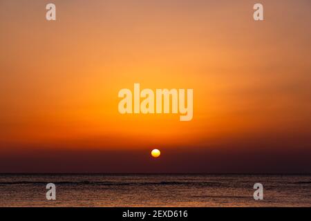 Bright sunset with a big yellow sun under the sea surface. Stock Photo