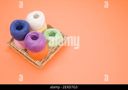 Multi-colored yarn balls in the peach color background with copy space on the right Stock Photo