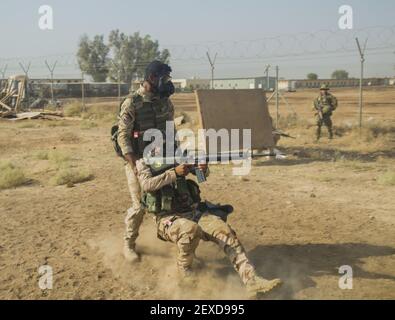 An Iraqi soldier assigned to the 71st Iraqi Army Brigade practices dragging casualty to cover while under fire during patrol exercise at Camp Taji, Iraq, Oct. 15, 2015. Iraqi soldiers performed basic drills while wearing a protective mask in order to simulate the vigorous environment created by a biochemical attack. Participating in this type of training at the Camp Taji building partner capacity site will prepare the soldiers for potential biochemical attacks when fighting against the Islamic State of Iraq and the Levant. (Photo by Spc. William Marlow/U.S. Army) *** Please Use Credit from Cre