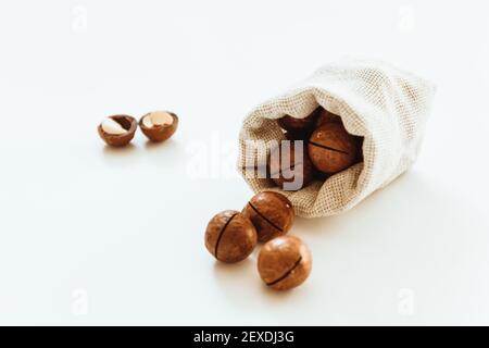 Fresh canvas bag with tasty organic macadamia nuts on white table Stock Photo