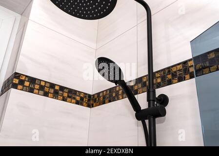 A modern, black metal shower with small and large rain shower, placed on tiles. Stock Photo