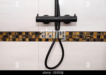 Black metal shower tap with temperature control, covered with a delicate white water stone. Stock Photo