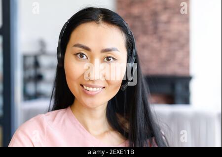 Close-up portrait of smiling Asian woman wearing wireless headset, assistant and support concept Stock Photo