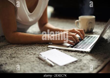 Close-up of woman hands working on laptop by a steaming cup of hot drink. Remote working from home/ start-up lifestyle, female entrepreneurial concept Stock Photo