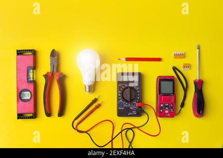 Flat lay composition with electrician's tools and copy space for text on yellow background with shine