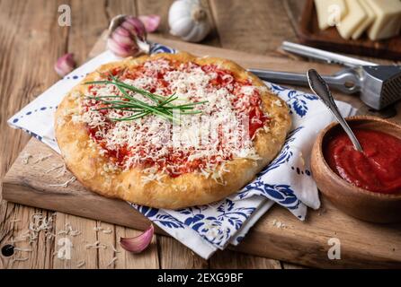 Classic Hungarian street food Langos, fried bread topped with ketchup, minced garlic and cheese on wooden background Stock Photo