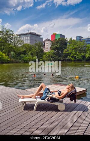 Young woman relaxing on lake pier. Holiday in the city.Frankfurt am Main, Hessen, Germany Stock Photo