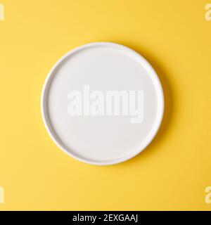 empty white plate on yellow background, top view Stock Photo