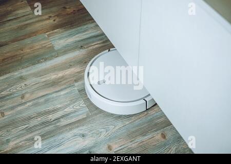 Robotic Vacuums, Robot Mops. Smart home. Automatic robotic vacuum cleaner on laminate wood floor, smart cleaning technology Stock Photo