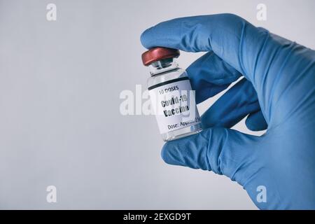 Hand in blue glove holding vial of Covid-19 vaccine Stock Photo