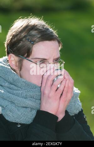Woman drinking hot coffee from a thermos mug Stock Photo