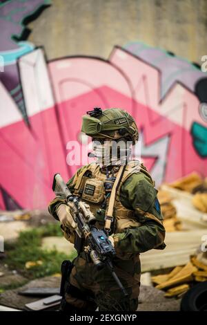 A shallow focus of a special force soldier in a camouflage holding a gun in an abandoned area Stock Photo
