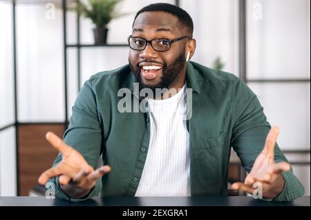 Portrait of a friendly successful multiracial black male freelancer or businessman, talking during video call with colleagues or friends, gesturing hands and smiling Stock Photo