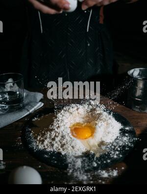 Woman adds an egg to the flour Stock Photo