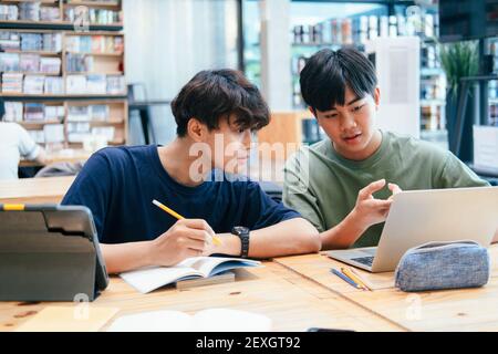 Young students campus helps friend catching up and learning. Stock Photo