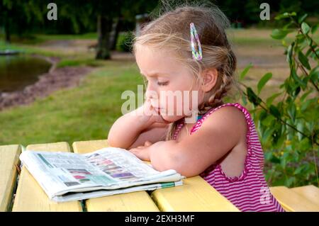 Cute little girl reading newspaper Stock Photo