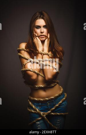 Brunette woman bound with rope prisoner in jeans Stock Photo