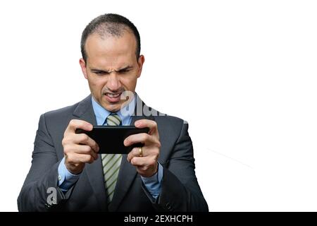 Mature man with suit and tie, playing on his smartphone and gritting his teeth. Stock Photo