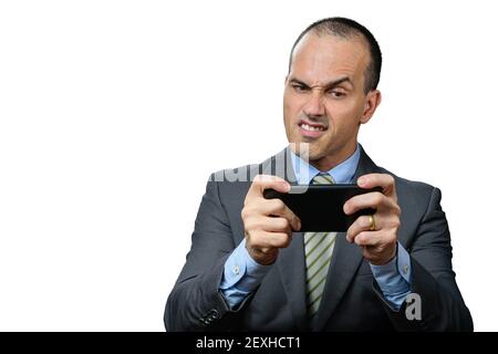 Mature man with suit and tie, playing on his smartphone and making a funny angry face. Stock Photo