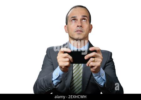 Mature man with suit and tie, holding his smartphone horizontally, worried and looking up. Stock Photo