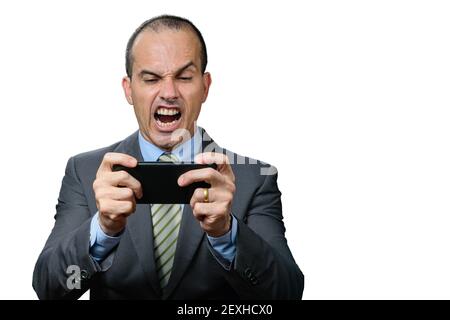 Mature man in a suit and tie, playing on his smartphone and with an angry face. Stock Photo