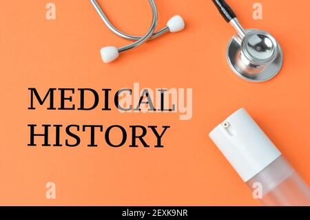 Hand sanitizer, stethoscope over orange background written with MEDICAL HISTORY. Stock Photo