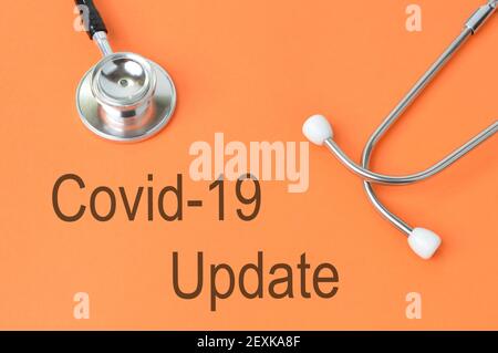 Stethoscope over orange background written with COVID-19 UPDATE. Stock Photo