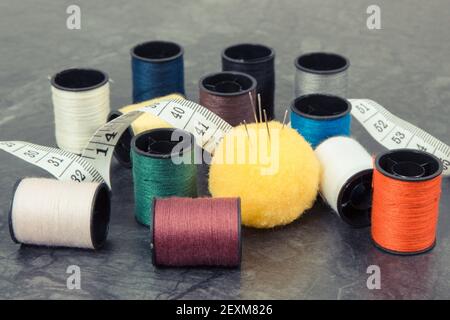 Accessories and tools for using in sewing and needlework. Spools of thread, needle and tape measure Stock Photo