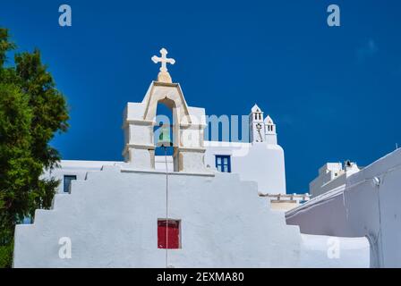 Typical bell tower or small belfry of a whitewashed Greek Orthodox church on a clear summer day. Greek island. Blue sky, no clouds. Upshot. Stock Photo