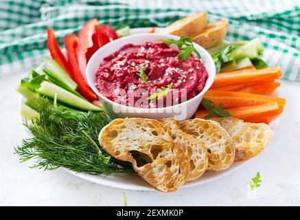 Roasted beet hummus with toast and vegetables on a light background. Beetroot hummus. Stock Photo