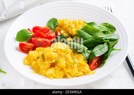 Breakfast. Scrambled eggs with cherry tomatoes, spinach  and corn. Stock Photo