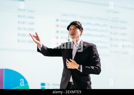 Asian Businessman Stands on Stage for Business Presentation Stock Photo