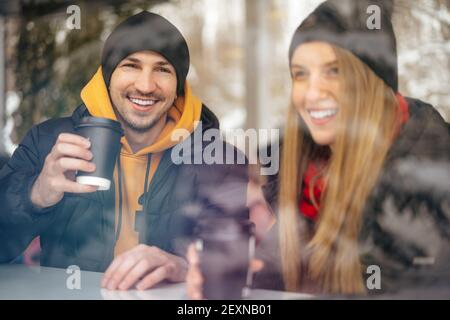 Young loving couple drinking coffee in a cafe behind the glass Stock Photo