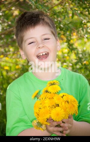 Laughing boy with a bouquet of dandelions Stock Photo