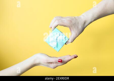 Male hand putting in female gift on yellow background closeup Stock Photo
