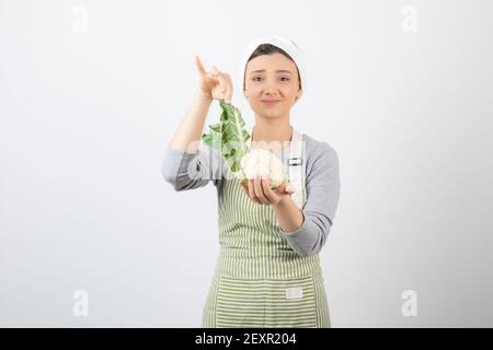 Photo of a young nice woman model in apron holding a cauliflower Stock Photo