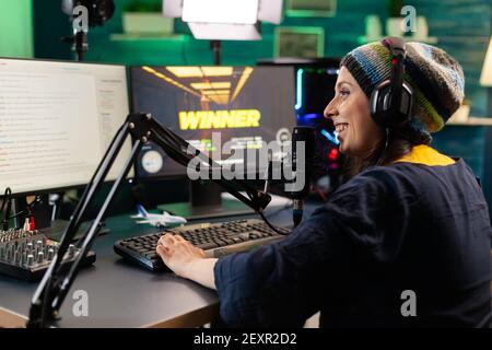 Back view of upseted streamer playing game competition using professional setup with streaming chat open. Gamer sitting on gaming chair using wireless controller and professional headphone Stock Photo