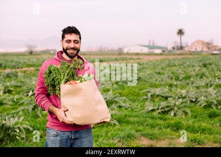 young entrepreneur farmer smiling with a burlap bag full of vegetables and fruits, concept of entrepreneurship in the countryside and ecological farmi Stock Photo