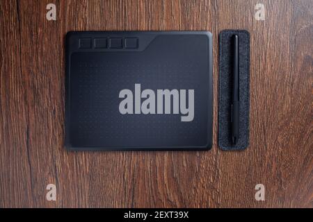 Ggraphic tablet drawing pad with digital pen stylus on felt pad on table flat lay Stock Photo