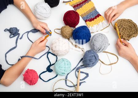 Different colored balls of yarn. Children's hands are crocheted and thread view frome above Stock Photo