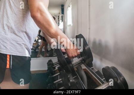 Hand gripping a dumbbell, on a dumbbell bench. Gym. Sports concept Stock Photo