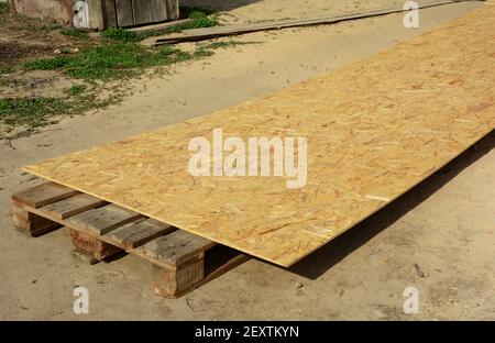 A close-up of OSB, oriented strand board, plywood sheet on the construction site as a roof sheathing material. Stock Photo
