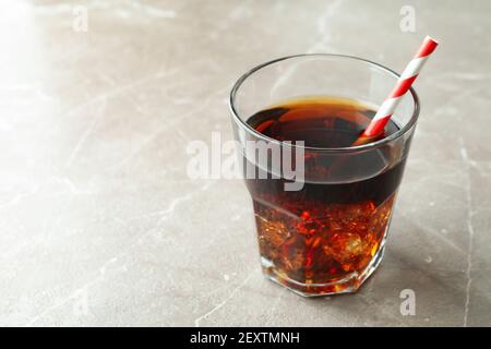 Glass of cola with ice cubes and straw on gray table Stock Photo