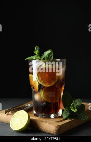 Board with glass of Cuba Libre against dark background Stock Photo